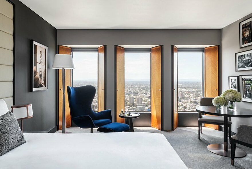 A hotel room with fresh flowers, city views and a blue velvet chair. 