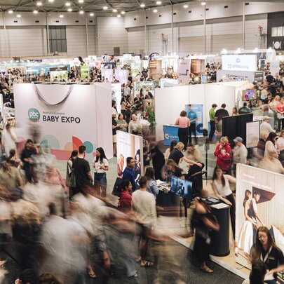 Looking down on a pregnancy and baby expo with many people moving around near booths. 