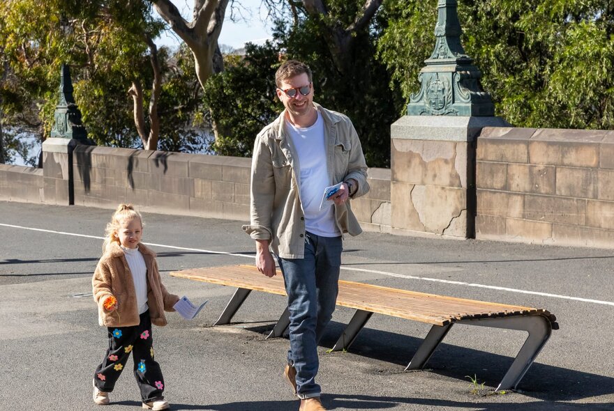 Adult and child walking across a bridge.