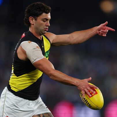A Richmond AFL football player about to kick the football on the field during a match.