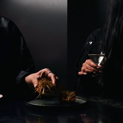 Hands holding drink glasses in a dark room.