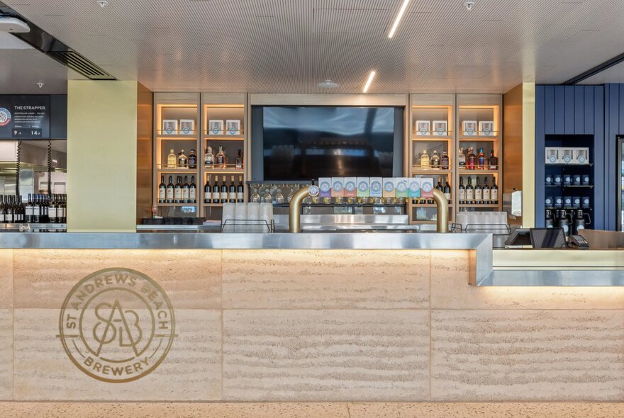 The large central bar area at St Andrews Beach Brewery at Melbourne Park, with taps and a row of drinks on the shelf behind the bar.