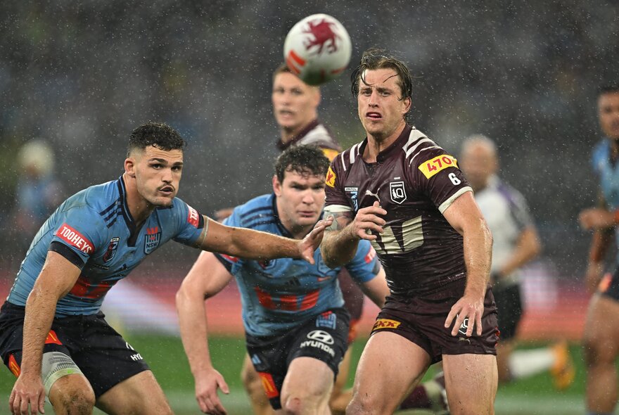 NRL State of Origin players on the field in the rain, playing rugby.