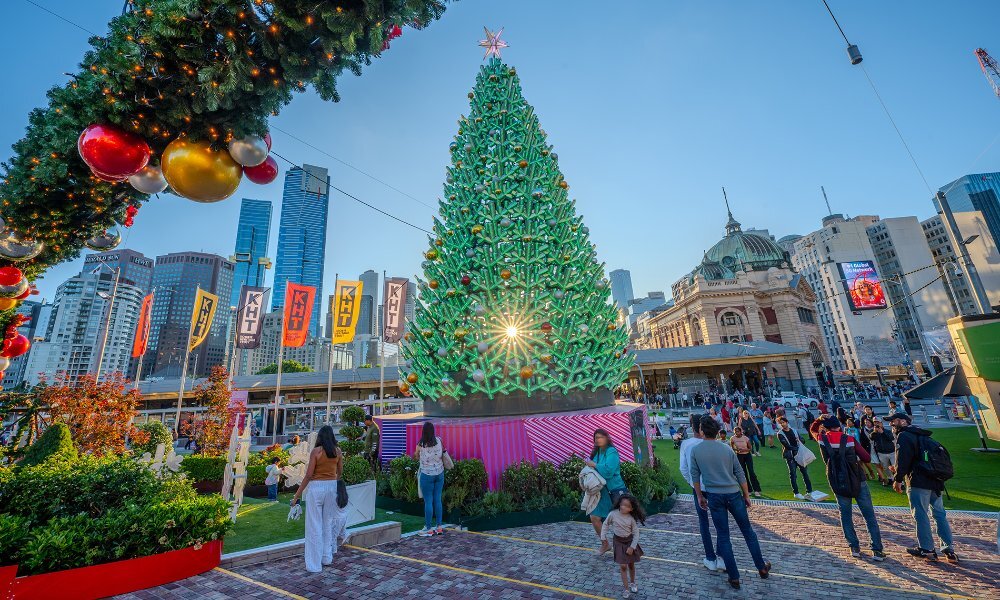 Families walking around a giant city Christmas tree.