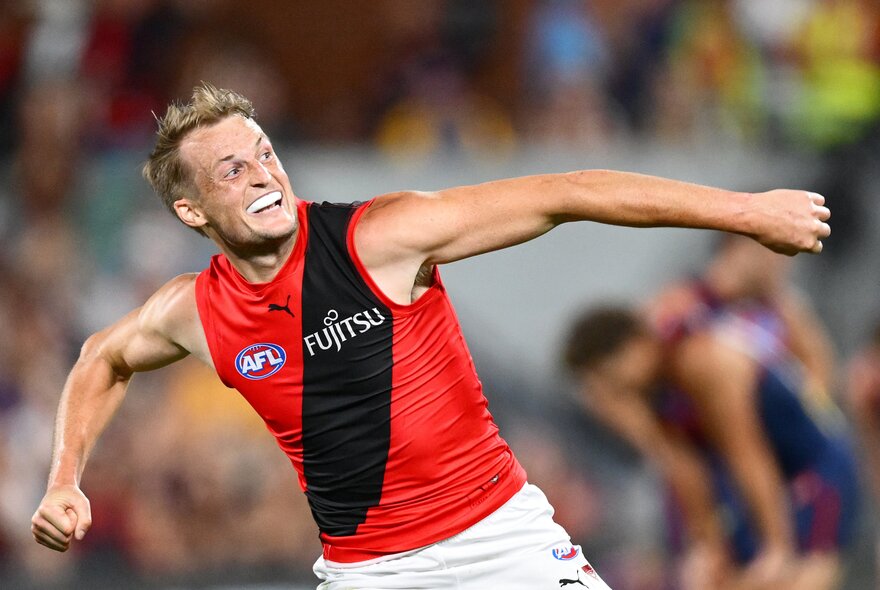 Essendon AFL football player with arms oustretched during a game.