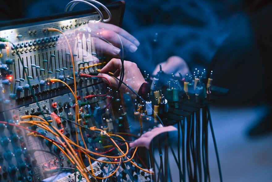 Hands connecting wires and sockets on a synthesiser.