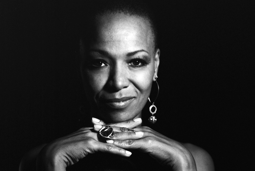 Woman leaning her chin on her hands, wearing rings and earrings.