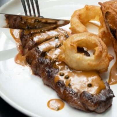 A porterhouse steak with mushroom sauce, and fried onion rings.