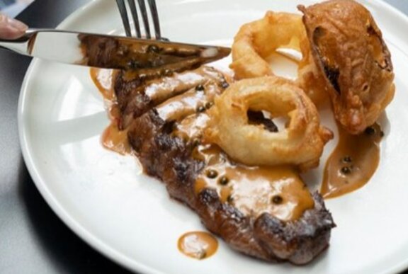 A porterhouse steak with mushroom sauce, and fried onion rings.