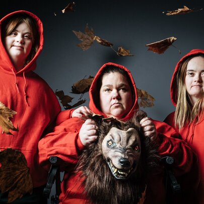 Actors in red hoods holding a wolf costume.