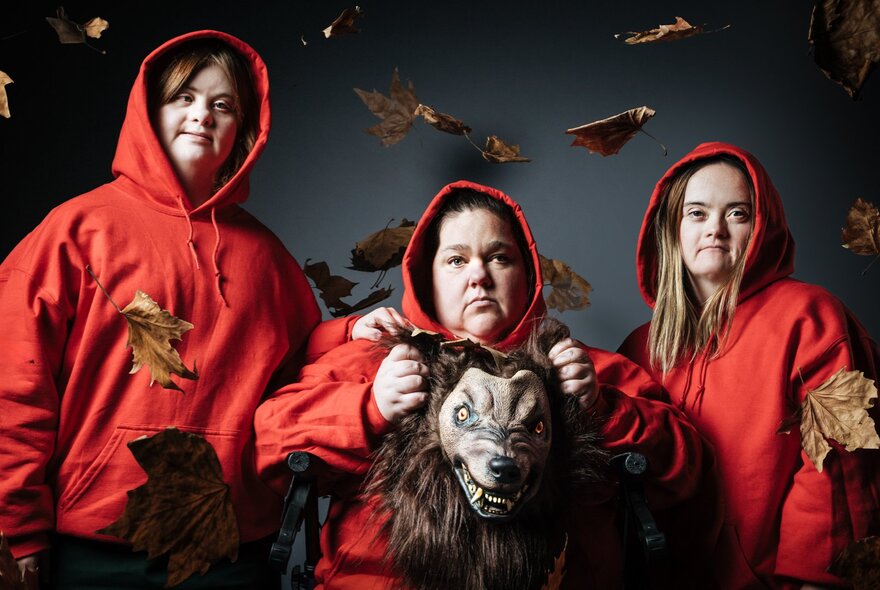 Actors in red hoods holding a wolf costume.