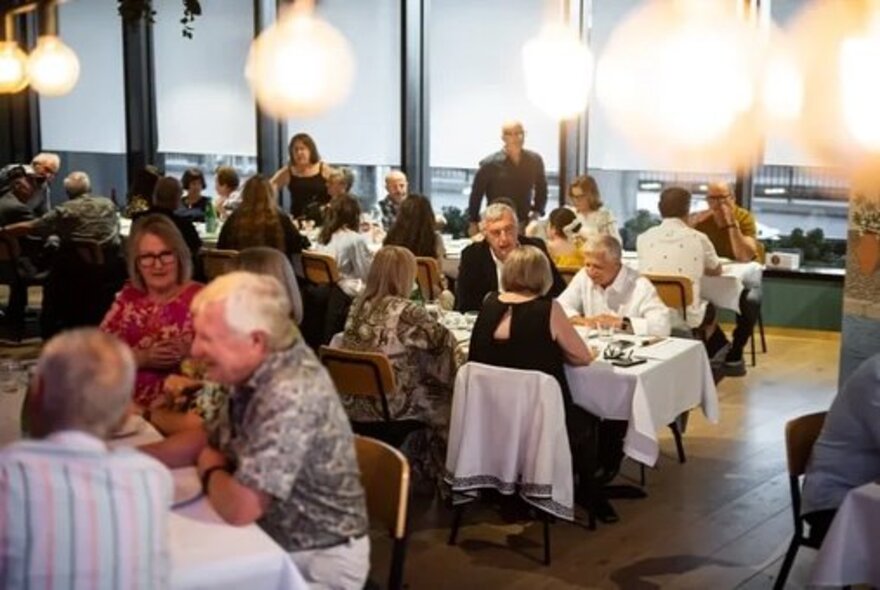 Patrons enjoying dinner at a crowded restaurant.