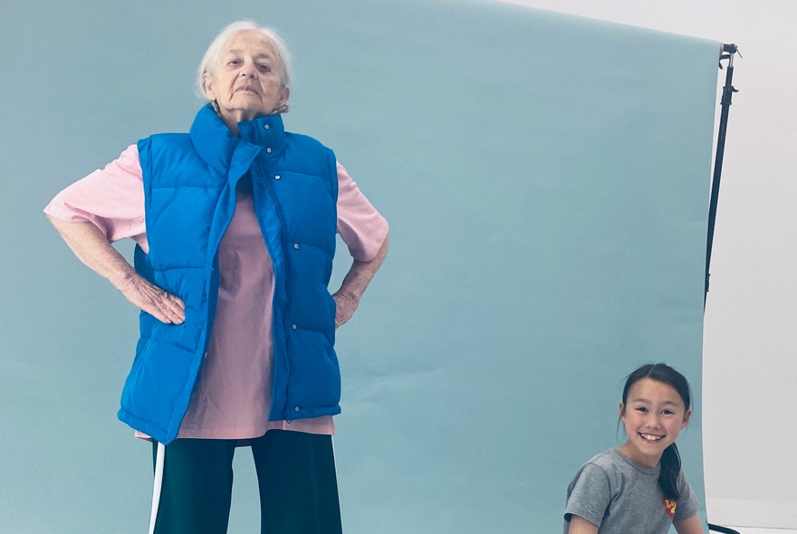Older person standing with hands on hips while a child looks on laughing.