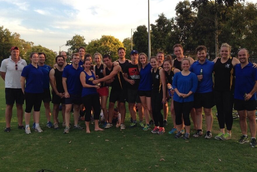 Large group of mixed football players standing in a row on the field.