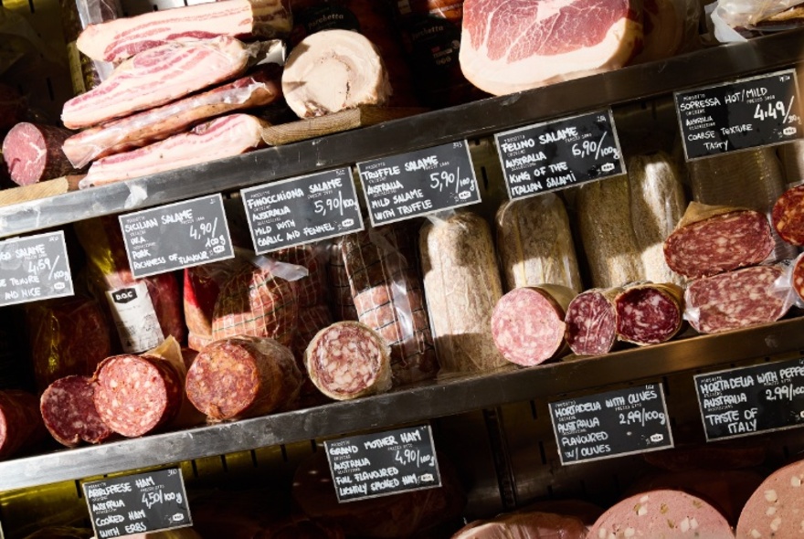Interior of D.O.C Delicatessen showing shelves of prosciutto, salami and other cured meats.