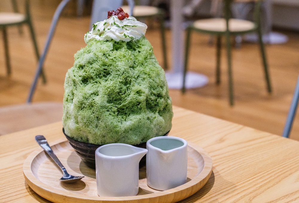 A matcha shaved iced dessert with cream on top
