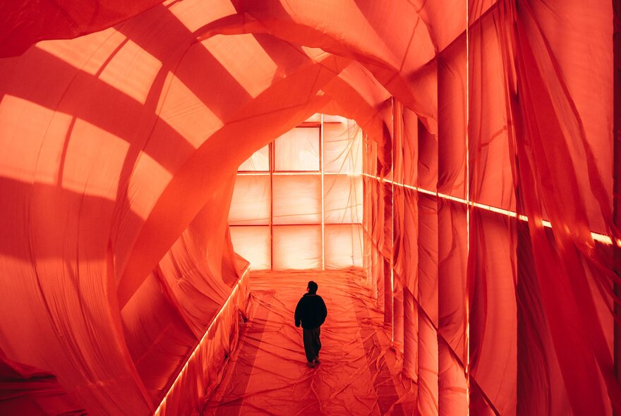 A person walking through a large hallway covered in red material.
