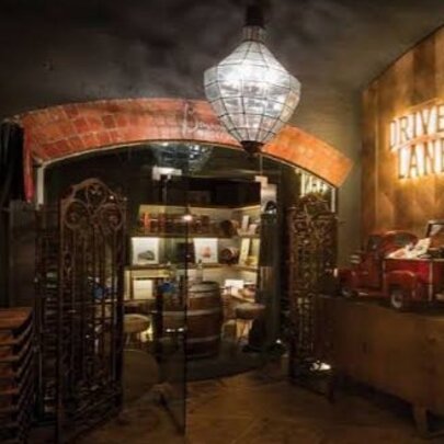 An underground bar entrance with a crystal chandelier hanging from the dark ceiling illuminating a brick archway.
