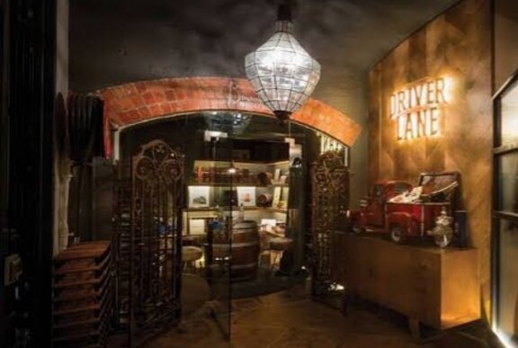 An underground bar entrance with a crystal chandelier hanging from the dark ceiling illuminating a brick archway.