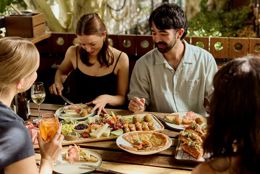 A group of people enjoying share plates at an outdoor restaurant.