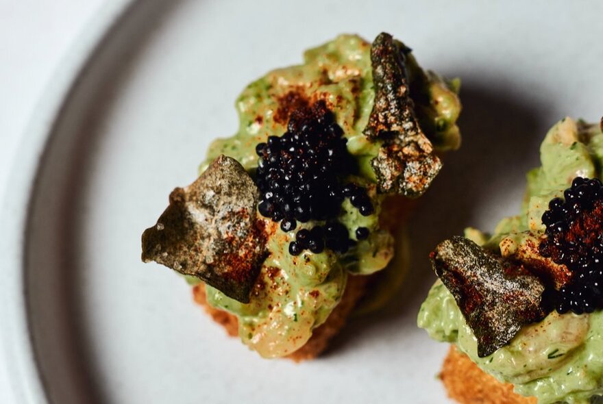 Avocado on toast with grilled garnish and caviar.