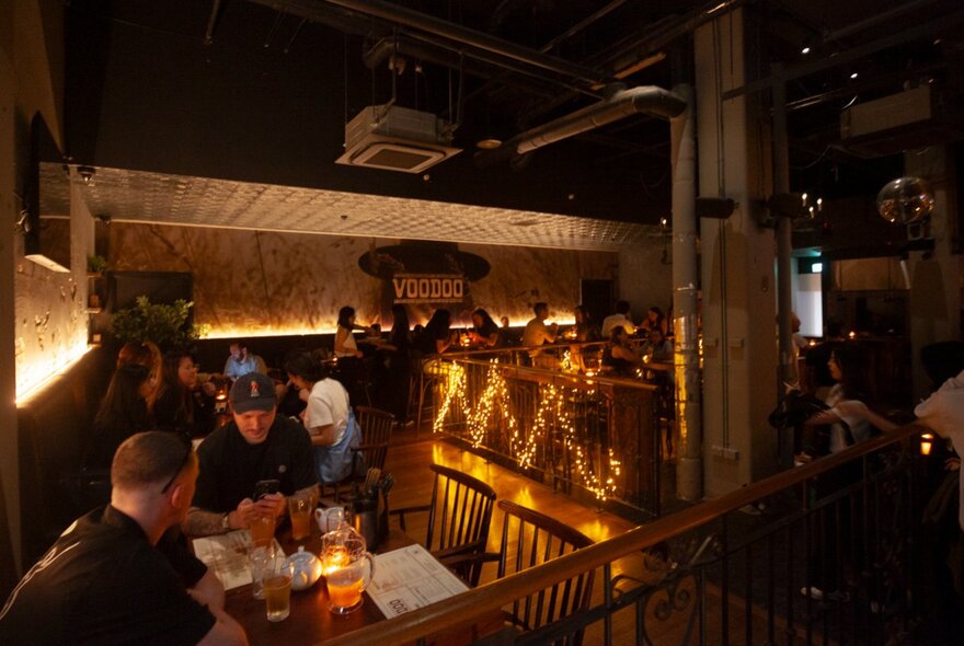 The inside of a dimly lit venue with patrons enjoying drinks at tables.