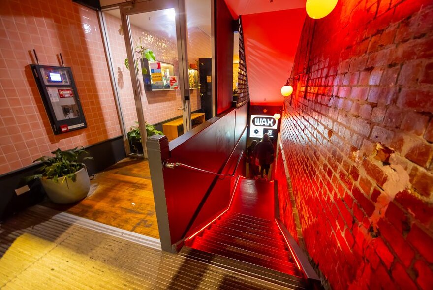 A staircase leading to a basement venue with glowing red lights.