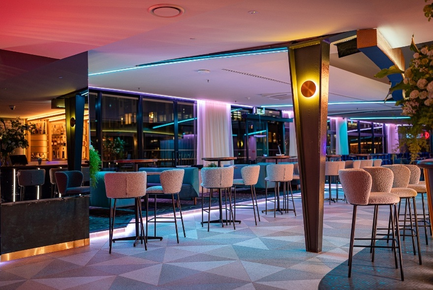 A retro neon interior of a bar with high stools. 