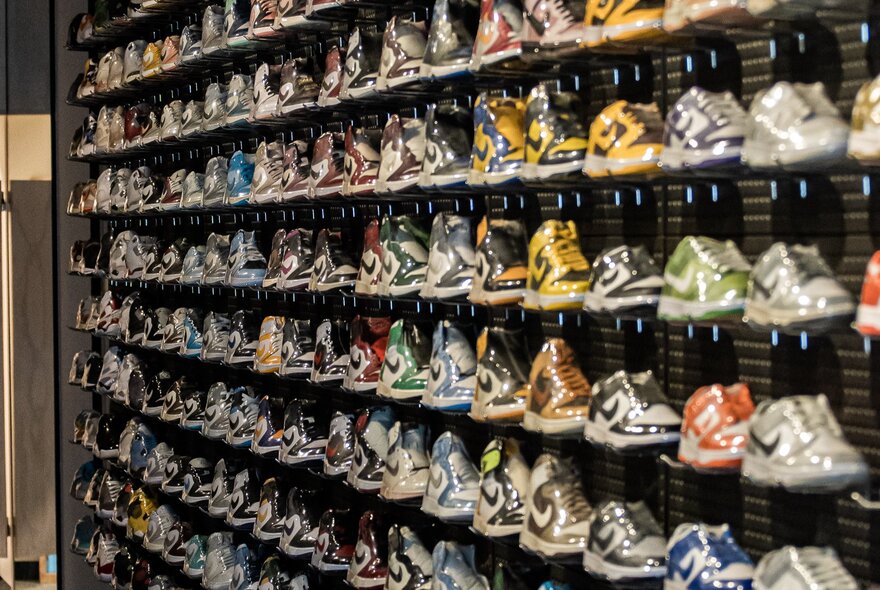 Rows of sneakers lined up in rows on a wall in a store.