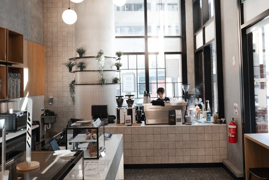 An indoor shot of a modern coffee shop interior with high ceilings and large windows.