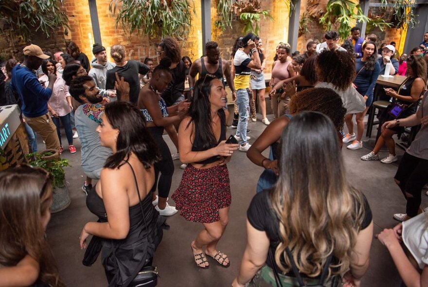 People dancing and mingling at an indoor / outdoor venue.