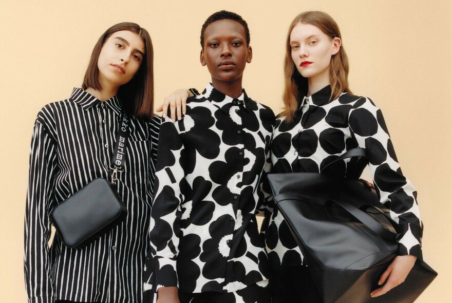 Three women wearing tops with bold black and white designs.