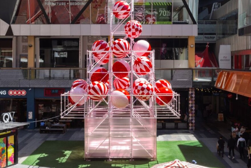 An abstract Christmas tree sculpture made of pink scaffolding and baubles.