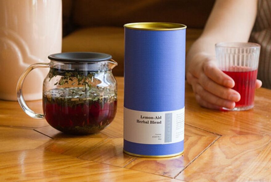 A can of tea leaves next to a teapot