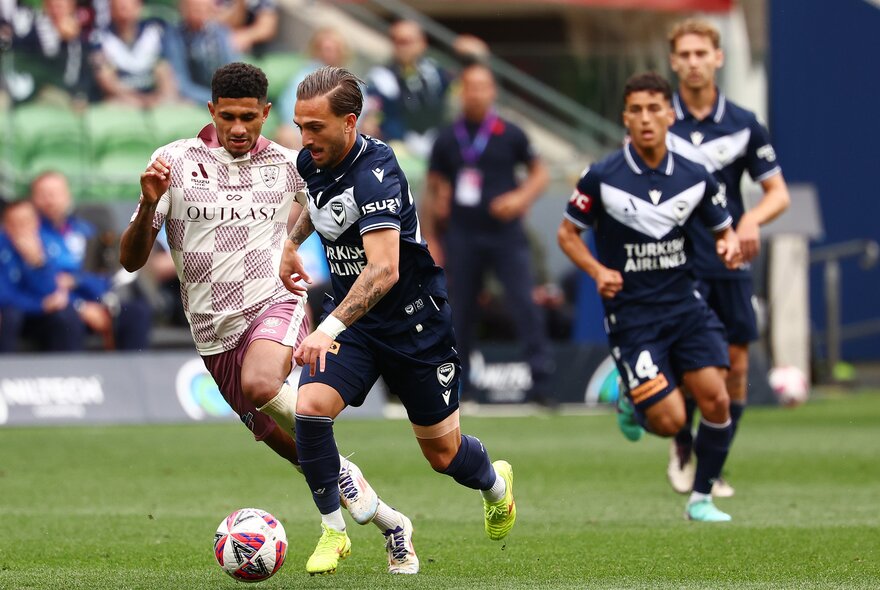 Soccer players on a field running after a ball.