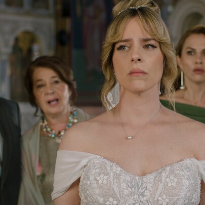 A still from a movie showing an actress dressed as a bride with three people behind her, all looking pensive.