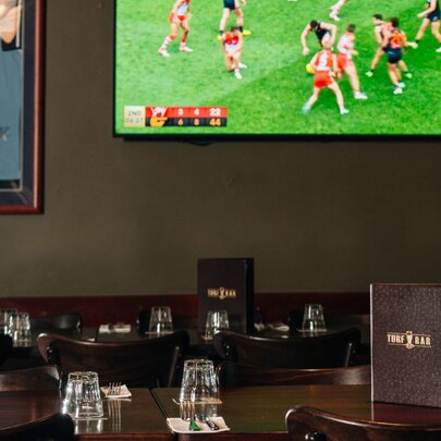 A room inside the Turf Sports Bar with a TV on a wall screening an AFL football match.