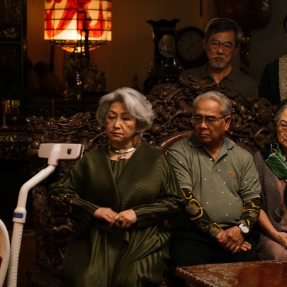 A still image from the film A Useful Ghost wuth people sitting starting at the head of a vacuum cleaner. 