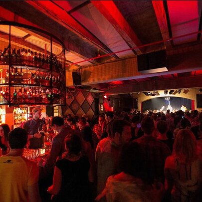 Crowded venue with red-lit bar.