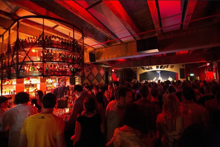 Crowded venue with red-lit bar.