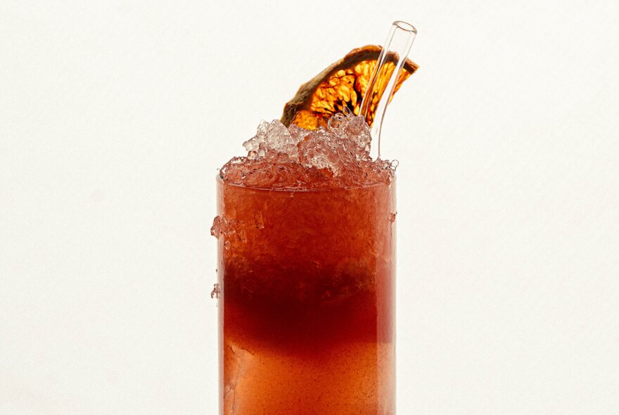 A reddish coloured cocktail served in a tall glass, with a slice of dried orange as a garnish.