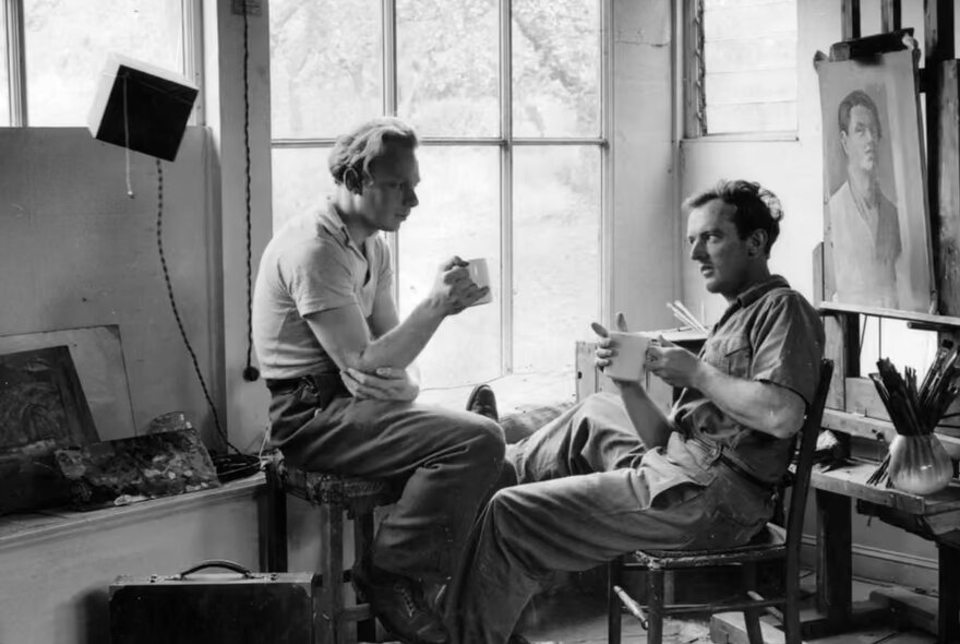 A black and white photograph of two artists sitting in a sunlit studio at the Abbey Art Centre, the iconic 1940s post-war artists' colony.