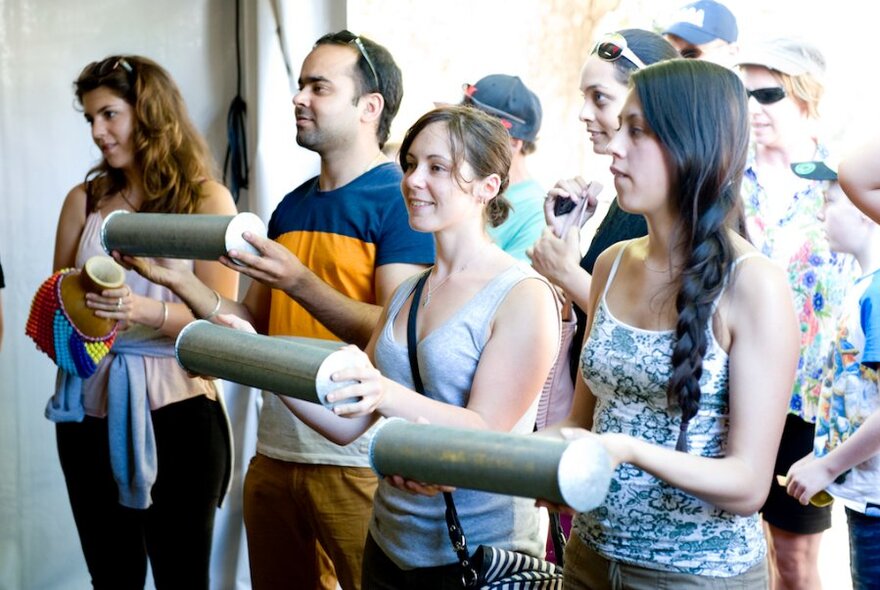 A small group of people all holding an African percussion instrument. 