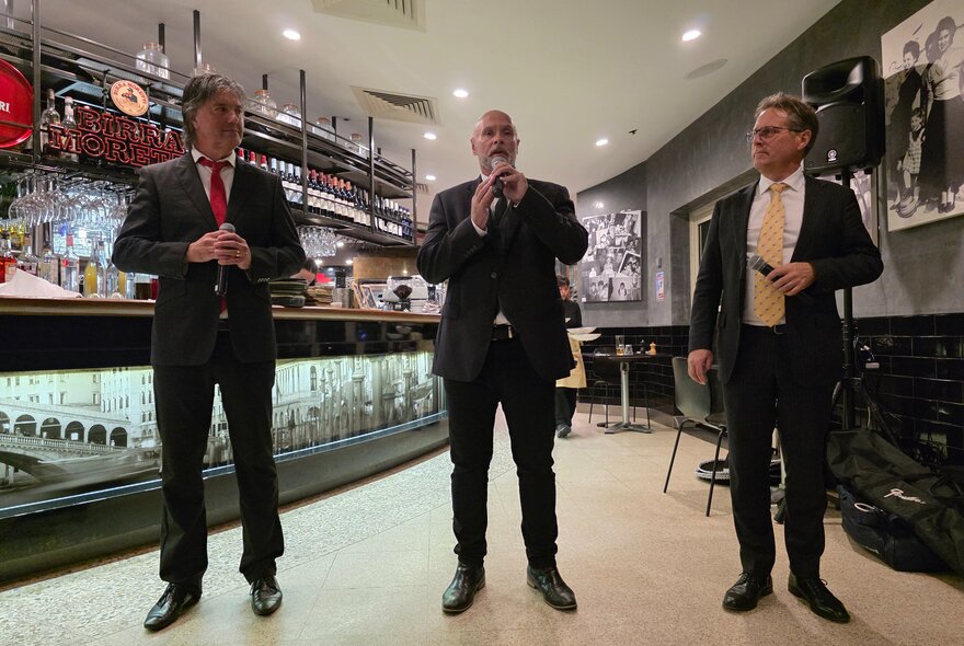 Three male singers in a a restaurant setting. 