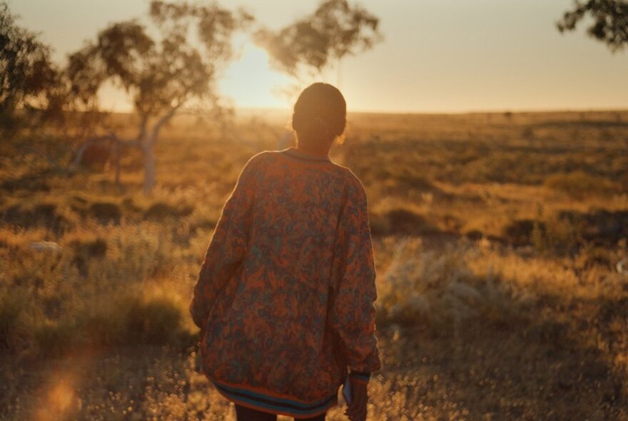 A still from an Australian movie, with a young Indigenous woman walking through the arid Australian landscape.