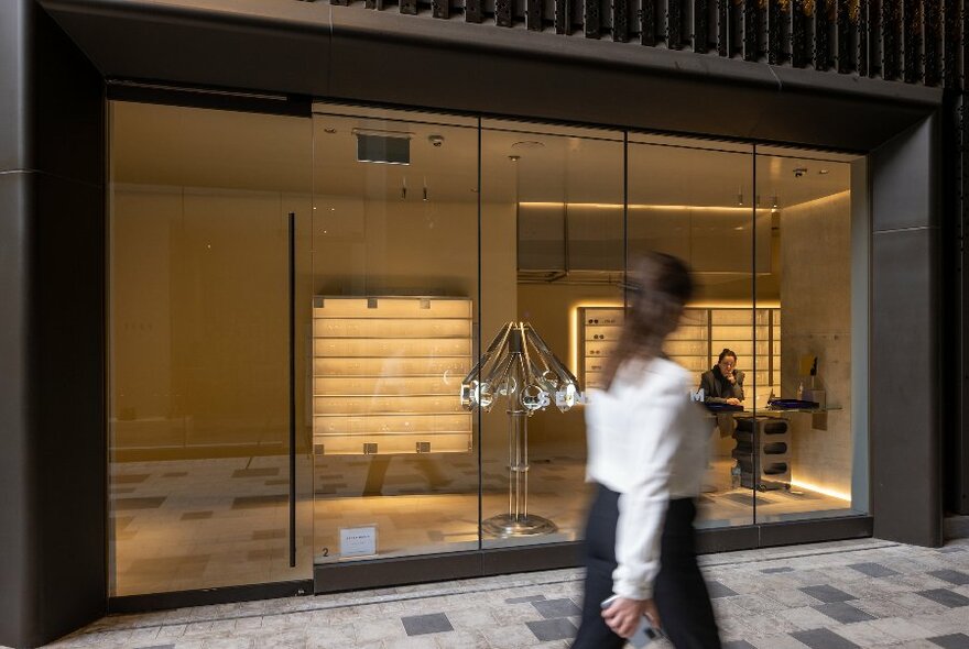 A woman walking past a warmly lit store