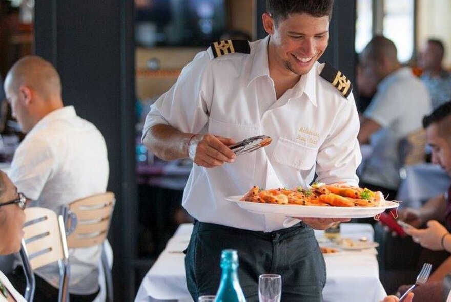 A sailor holding a platter of food, ready to serve.