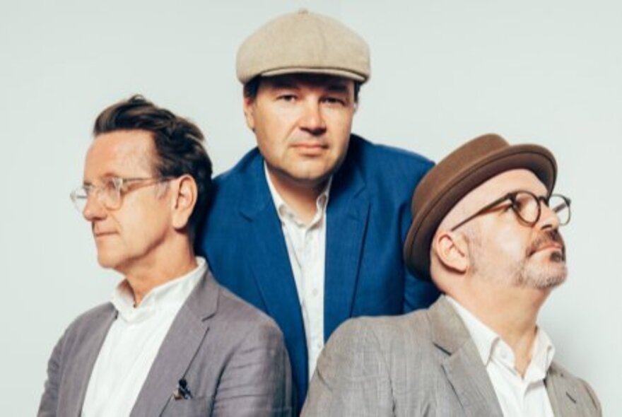 Jake Mason Trio, three men wearing blazers, two with hats and glasses.