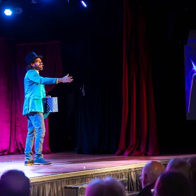 The Great Armando, a children's magician performing on stage in front of a seated audience.