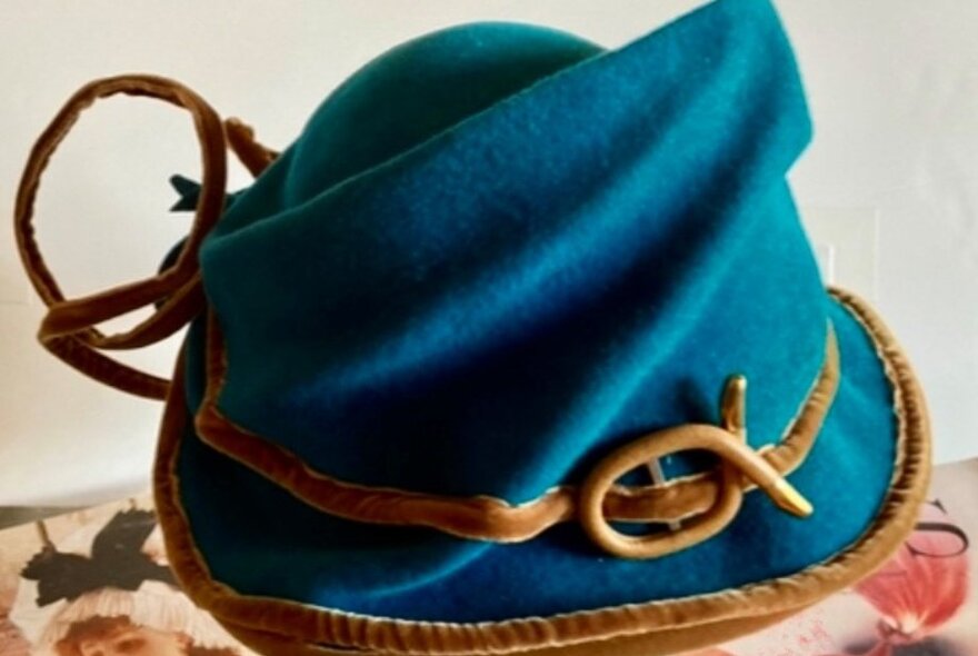 A blue turban-style winter hat with brown twig trim.